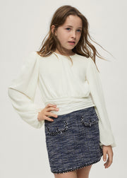 Girl wearing Mayoral cream balloon sleeve pleated blouse styled with navy tweed skirt