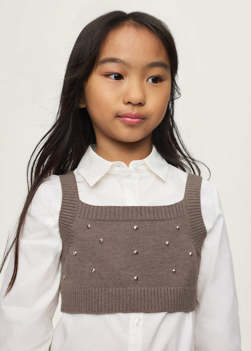 Girl wearing Mayoral cream shirt with black rhinestone knit vest layered over – on model full body view
