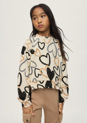 Girl wearing Mayoral all-over heart print sweatshirt styled with camel cargo trousers – on model full body front view