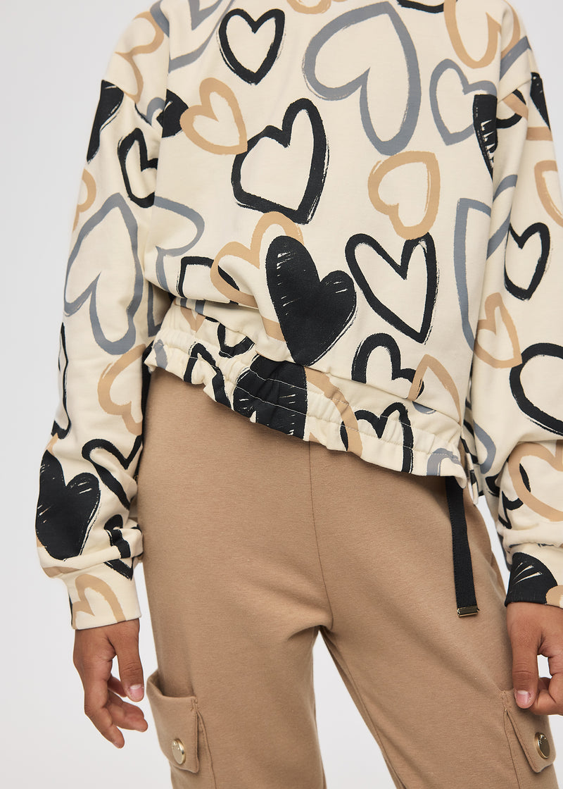 Girl wearing Mayoral heart print sweatshirt – close-up of drawstring gathered hem with black toggle tabs