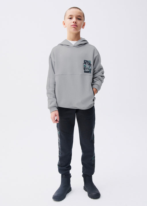 Boy wearing Mayoral Nukutavake black camo side panel joggers with matching black hoodie holding basketball – on model full body front view