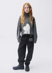Girl wearing Mayoral black barrel-leg jeans with grey turtleneck heart knit and black boots – on model full body front view