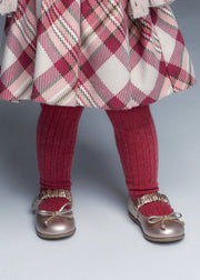Girl wearing Mayoral raspberry ribbed tights with tartan skirt and rose gold Mary Jane shoes – on model legs detail view