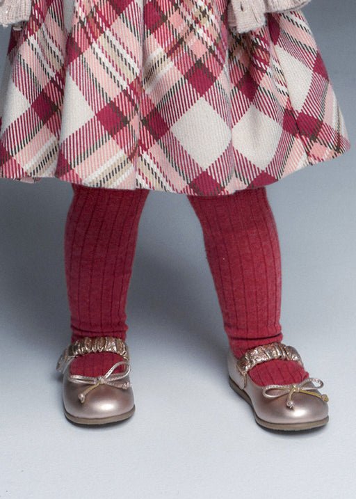 Girl wearing Mayoral raspberry ribbed tights with tartan skirt and rose gold Mary Jane shoes – on model legs detail view